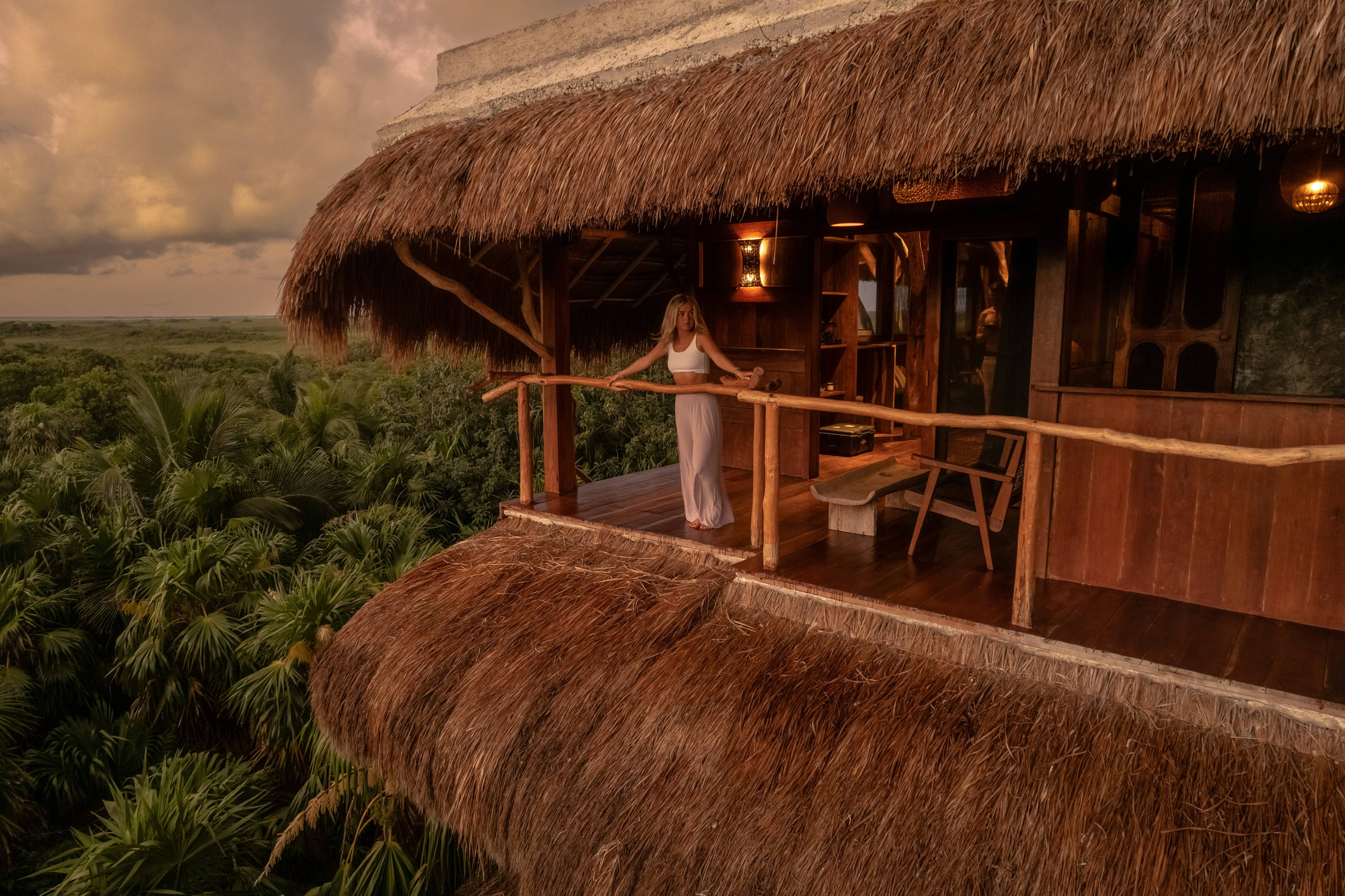 Luxury tropical resort villa with thatched roof overlooking lush vegetation